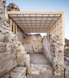 an open air structure in the middle of some rocks and dirt with a sky background