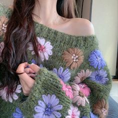 a woman wearing a green sweater with flowers on it