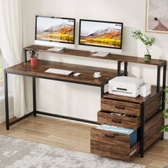 two computer monitors sitting on top of a wooden desk next to a printer and monitor