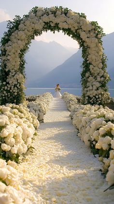 a bride and groom standing in the middle of a flower lined path