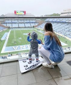 a woman and child sitting on top of a football field