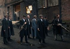 a group of men standing next to each other in front of an old factory building