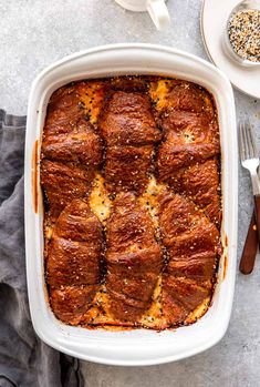 a casserole dish with meat and cheese in it on a table next to two forks