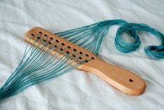 a close up of a wooden comb on a bed with blue string and thread spools