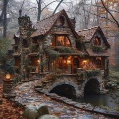 a stone house in the woods with lights on