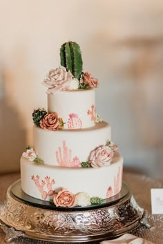 a three tiered cake with flowers and cactus on top