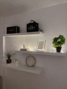 a white shelf with a clock, plant and other items on it's ledge