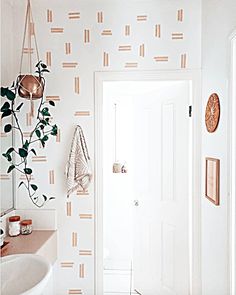 a white bathroom with a plant hanging on the wall and a sink in front of it