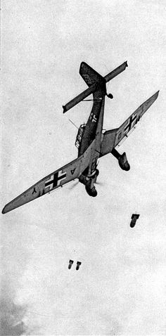 an old airplane flying in the sky with two parachutes attached to it's wings