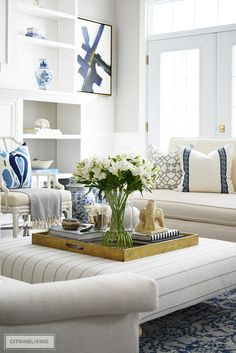 a living room filled with white furniture and lots of flowers on top of a coffee table