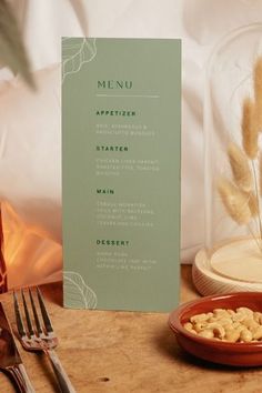 a menu sitting on top of a wooden table next to a plate of food and a fork