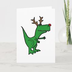 a green dinosaur with antlers on it's head is standing in front of a vase