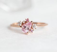 a close up of a pink diamond ring on a white surface