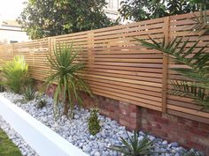 a wooden fence next to some plants and rocks