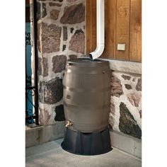 a large metal barrel sitting in front of a stone wall next to a white pipe