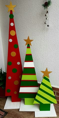 three wooden christmas trees on display in front of a wall