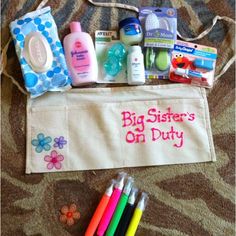 the contents of a diaper bag sitting on top of a bed next to markers, toothbrushes and other items