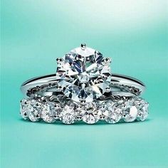 two wedding rings with an engagement ring and diamond band on top of each other in front of a turquoise background