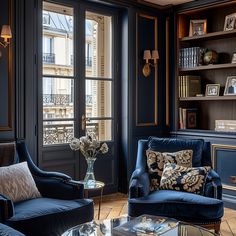 a living room filled with blue couches next to a tall book shelf full of books