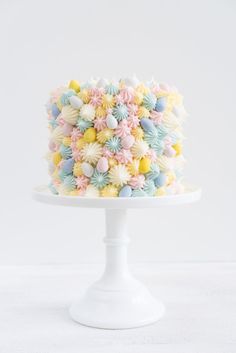 a multicolored cake on a white pedestal