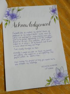 a piece of paper that has some writing on it with flowers and leaves around it