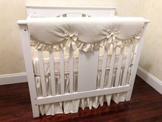 a white crib with ruffles and bows on the bedding is shown