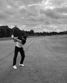 a man swinging a baseball bat on top of a tarmac with trees in the background