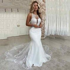 a woman in a white wedding dress standing next to a wall and looking at the camera