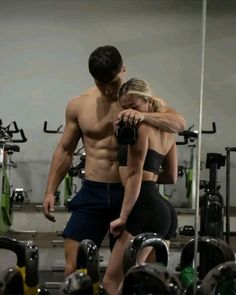 a man and woman standing next to each other in a gym with dumbbells