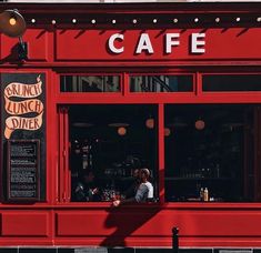 a red restaurant with people sitting at the window