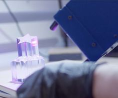 a person is using a machine to cut glass pieces on a piece of paper that has been placed on top of it