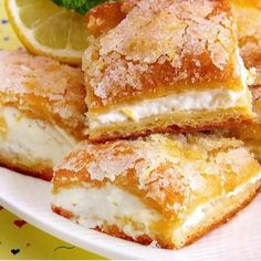 lemon filled pastries on a white plate with mint sprig and lemon wedges