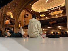 two people sitting on the floor in an auditorium