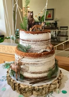 a three tiered cake with frosting and deer figurines