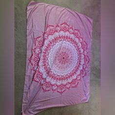 a pink and white blanket laying on top of a floor next to a carpeted floor