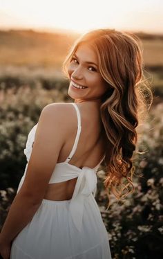 a woman standing in a field smiling at the camera