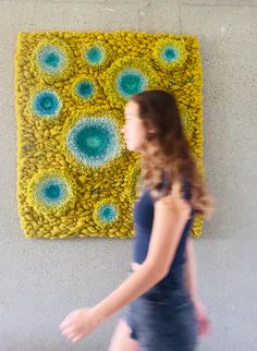 a woman walking past a yellow and blue artwork on the wall in front of her