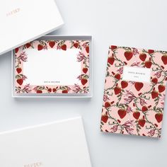 two boxes with strawberries on them are next to each other and one has a notepad in it