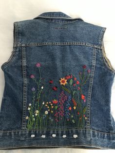 an embroidered denim vest with flowers on it