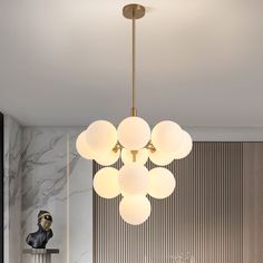 a modern chandelier hanging from the ceiling in a room with marble walls and flooring