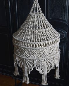 a white crocheted hanging basket with tassels on it's sides