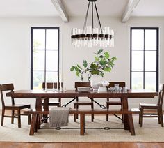 a dining room table with chairs and a chandelier hanging from it's ceiling