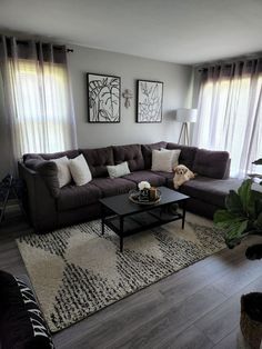 a living room filled with furniture and windows covered in draping next to a rug