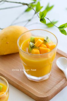 a glass filled with fruit sitting on top of a wooden cutting board