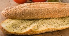 two loaves of bread sitting on top of a wooden cutting board next to tomatoes