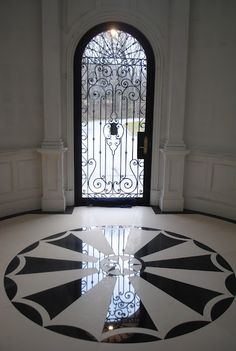 the entrance to a building with an ornate door and black and white design on the floor