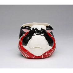 a black and white cow is sitting in a red bowl