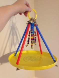 a person is holding a yellow tray with beads on it and a pair of scissors hanging from the top