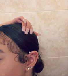 a close up of a person's head with hair in a bun and earring