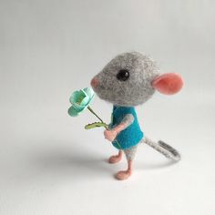 a needle - felt mouse holding a flower in its hand and wearing a blue shirt